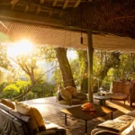 What unique architectural style sets The Highlands apart from traditional canvas safari camps?